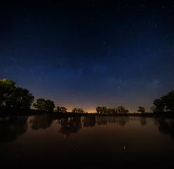  Glad oppervlak van bosmeer op een achtergrond van de nachtelijke hemel © lexuss