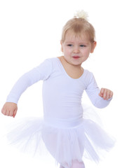 Fototapeta na wymiar The little blonde girl in a white sports dress up
