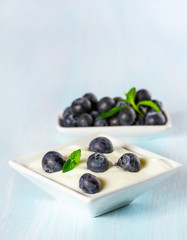 Yogurt with ripe blueberries on a wooden background.
