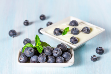 Naklejka na ściany i meble Yogurt with ripe blueberries on a wooden background.