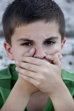 Portrait of a child covering his mouth with his hands