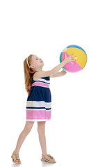Little girl holding a beach ball in his outstretched hands