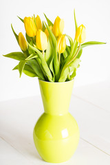 A round green vase full of tulips and leaves