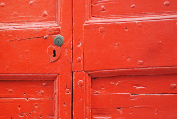 Detail of old wooden red painted door with heart shaped key hole