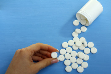 Pills from bottle on the blue background.