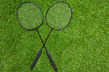 Two badminton rackets lying crossed on the grass