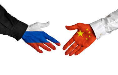 Russian and Chinese leaders shaking hands on a deal agreement