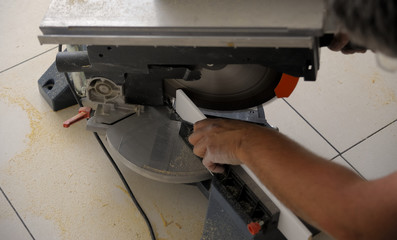 Closeup view of a man that is cutting wooden board electric circular saw. Focus is on the tools