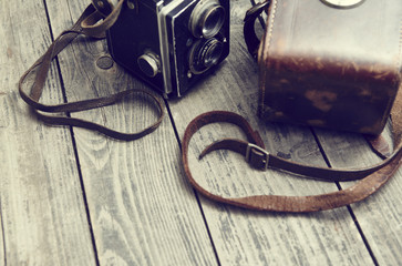 Old retro camera and belt bag (leather case) on vintage wooden boards abstract background