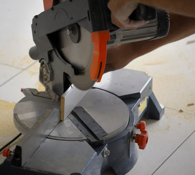 Closeup view of a man that is cutting wooden board electric circular saw. Focus is on the tools