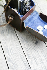 Plakat Old retro camera and belt bag (leather case) on vintage wooden boards abstract background