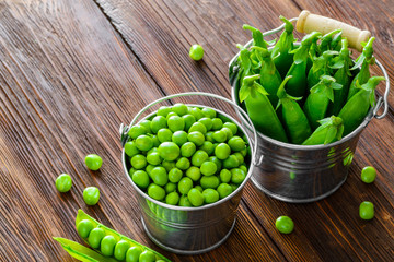 hearthy fresh green peas and pods on rustic wood table