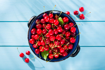 Cherries in bowl on blue wooden table top view