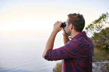 Young man looking out at the horizon with his binoculars