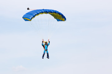 Parachutist in a blue suit on blue yellow parachute