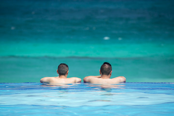 Coole Männer im traumhaften Pool mit Blick aufs Meer