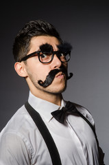 Obraz premium Young man with false moustache isolated on gray