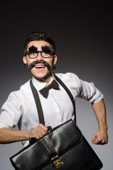 Young man with false moustache holding case  isolated on gray