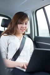 Beautiful asian young woman using laptop in car