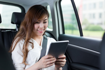 Beautiful asian woman using digital tablet in car