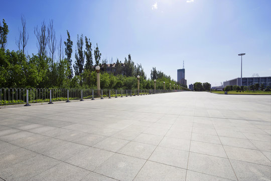 long empty footpath in modern city square with skyline.