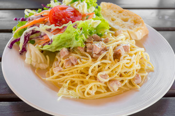 Spagetti pasta with ham and cream sauce with salad and bread.