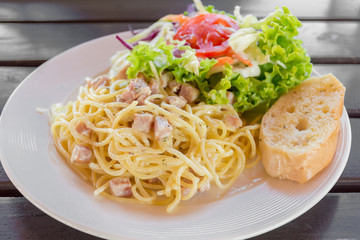 Spagetti pasta with ham and cream sauce with salad and bread.