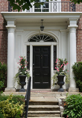 front steps of brick house with portico entrance and pink amaryllis
