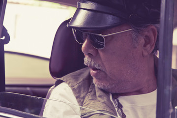 Older man with glasses driving a car