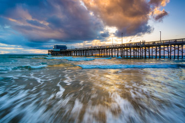 Waves in the Pacific Ocean and the Newport Pier at sunset, in Ne