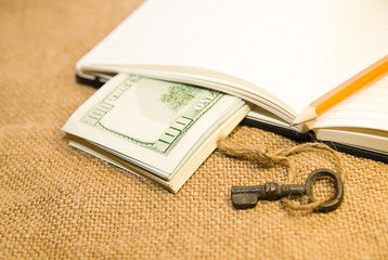 Opened notebook, pencil, key and money on the old tissue