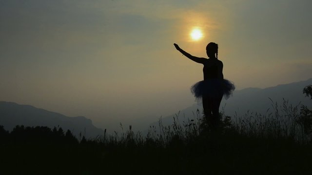Ballerina in silhouette at sunset in the mountains
