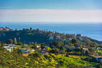 View of green hills and houses overlooking the Pacific Ocean, in © jonbilous