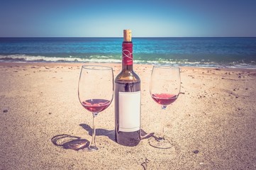 A bottle of wine and glasses on the beach - retro and vintage st