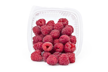 Box or punnet and spilled fresh ripe organic raspberries isolated on white background
