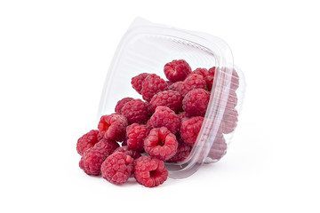 Box or punnet and spilled fresh ripe organic raspberries isolated on white background