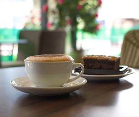 Cup of coffee and a cake on the table in cafe