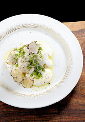Slices of tasty corn polenta with truffles mushrooms, asparagus, cheese and vegetables on a white plate on the table