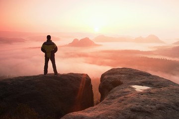 Moment of loneliness. Man on the rock empires  and watch over the misty and foggy morning valley to...