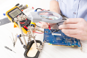 Serviceman checks PCB with a digital multimeter