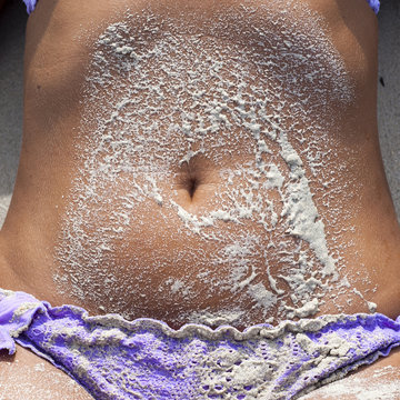 la sabbia di una spiaggia tropicale sull'ombelico di ragazza abbronzata
