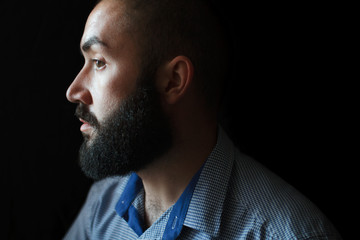 A man with a beard in a profile on a black background