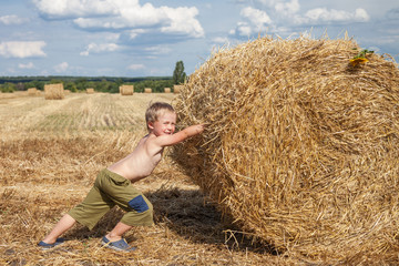 Boy pushes bale of straw
