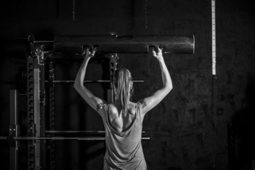 Athletic young woman showing muscles of the back and hands while training on black background - 85243172