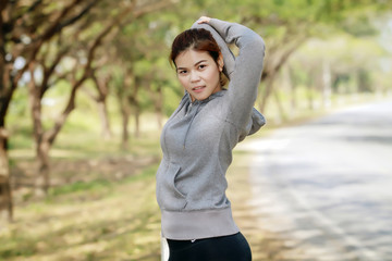 Athletic woman asia warming up and Young female athlete sitting on an exercising and stretching in a park before Runner outdoors, healthy lifestyle concept.