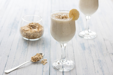 Healthy banana smoothies with oatmeal in a glass on a blue background