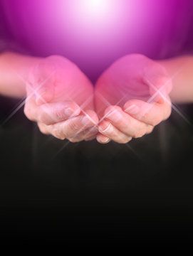Healer with Magenta Healing Orb Energy - female holding hands in cupped position with a bright magenta colored orb  energy hovering above and sparkles around finger tips