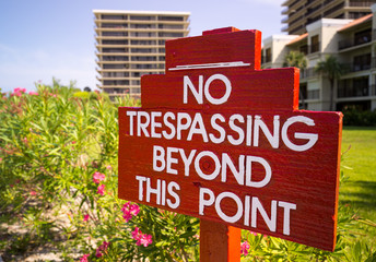 No Trespassing sign in red by flower gardens