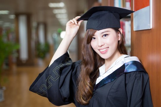 asian beautiful female student wearing academic dress in library