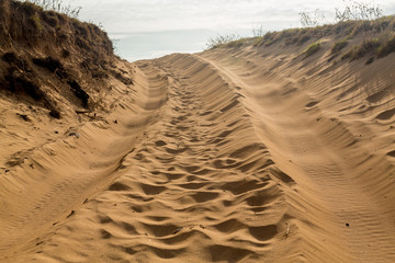 Tire tracks in sand dunes over hill © steheap